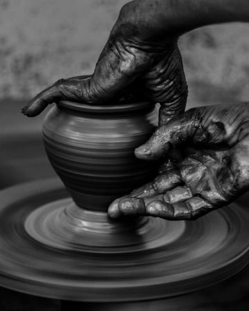 Hands sculpting a clay pot on a wheel